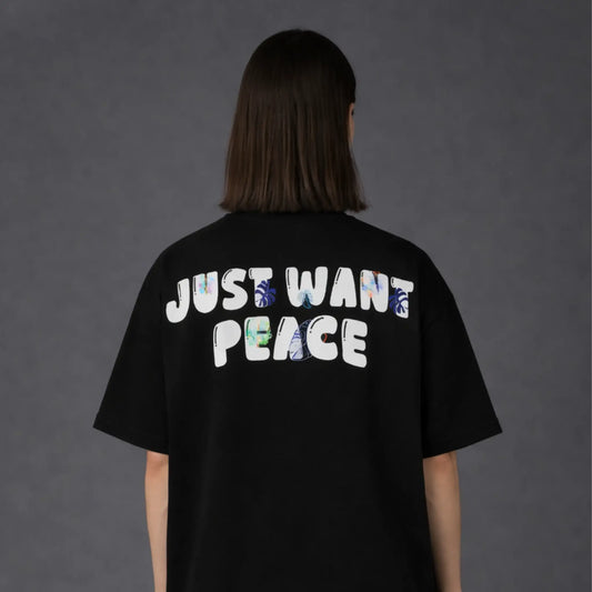 Person wearing a black t-shirt with 'JUST WANT PEACE' text on the back against a dark background