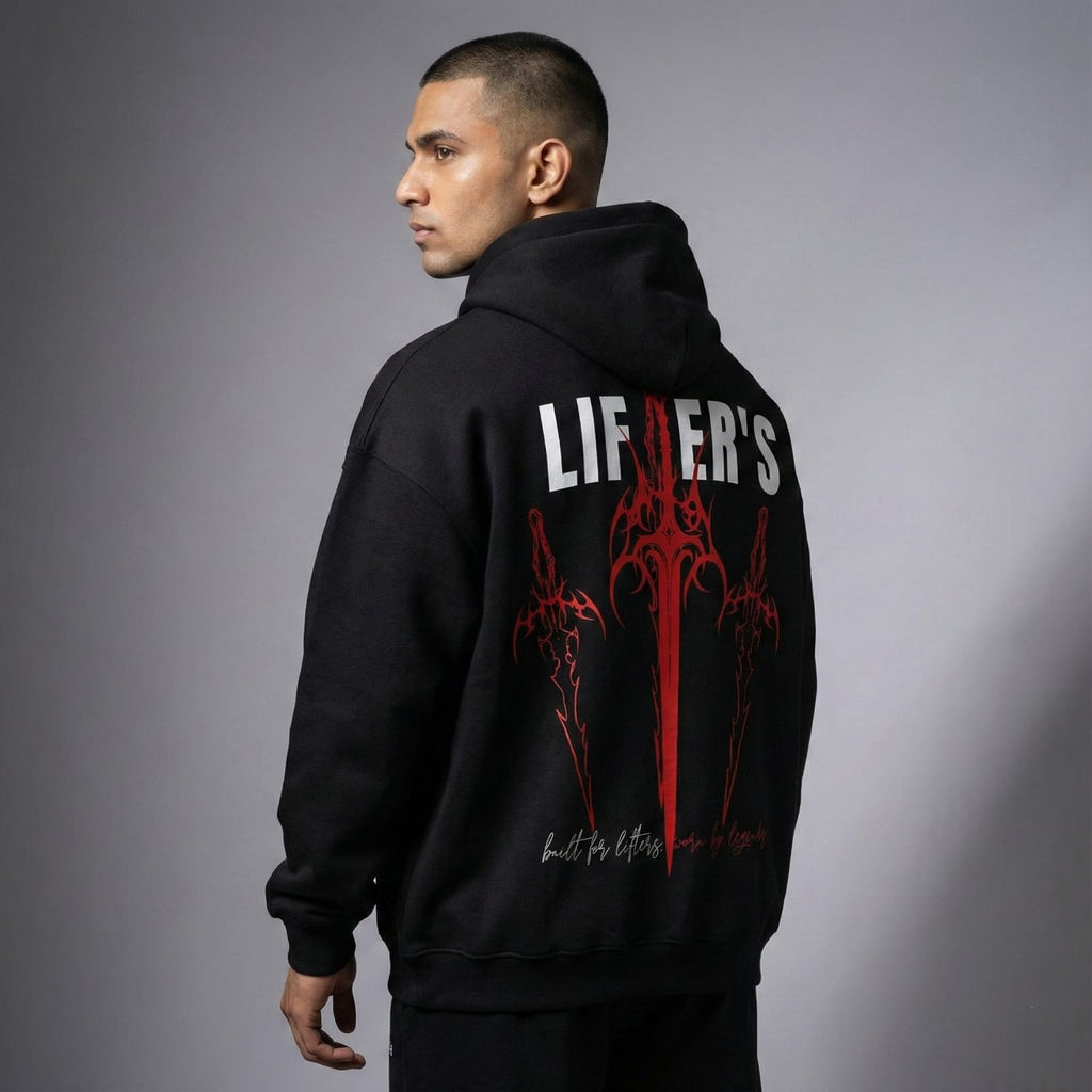 Person wearing a black hoodie with red and white graphics and text on the back against a gray background
