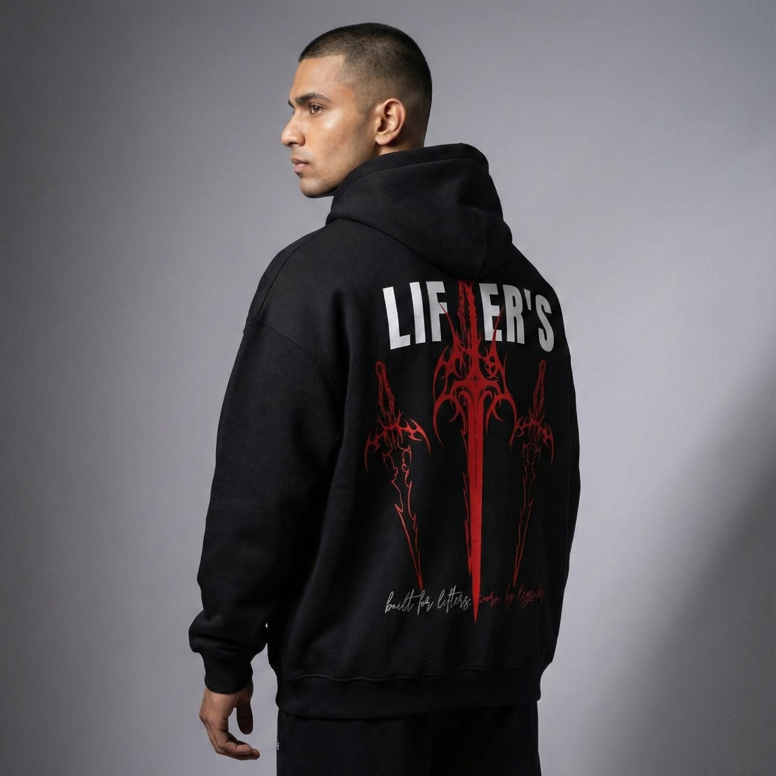 Person wearing a black hoodie with red and white graphics and text on the back against a gray background